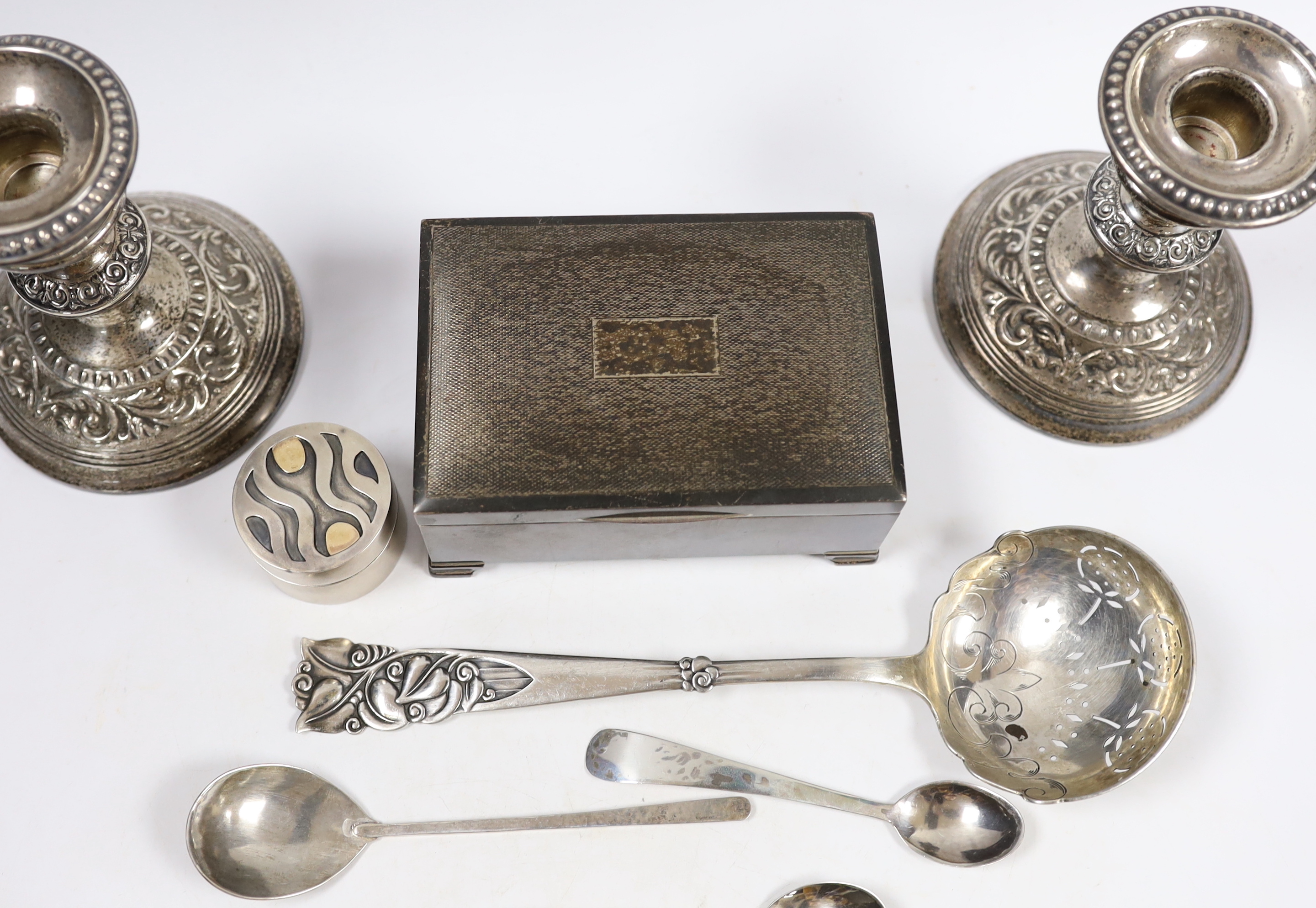 Sundry silver including a cigarette box, pair of dwarf candlesticks, modern silver circular pill box and three spoons, maker GR and a large early 20th century stylish Swedish white metal sifter ladle.